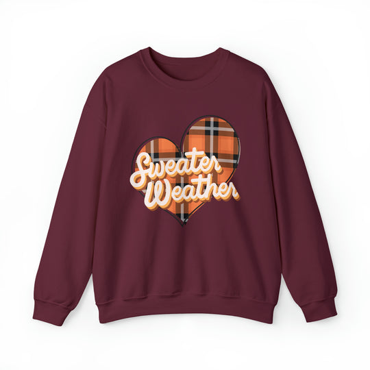A maroon Sweater Weather Crew, unisex heavy blend crewneck sweatshirt with a heart design. Made of 50% cotton, 50% polyester, ribbed knit collar, loose fit, and no itchy side seams.