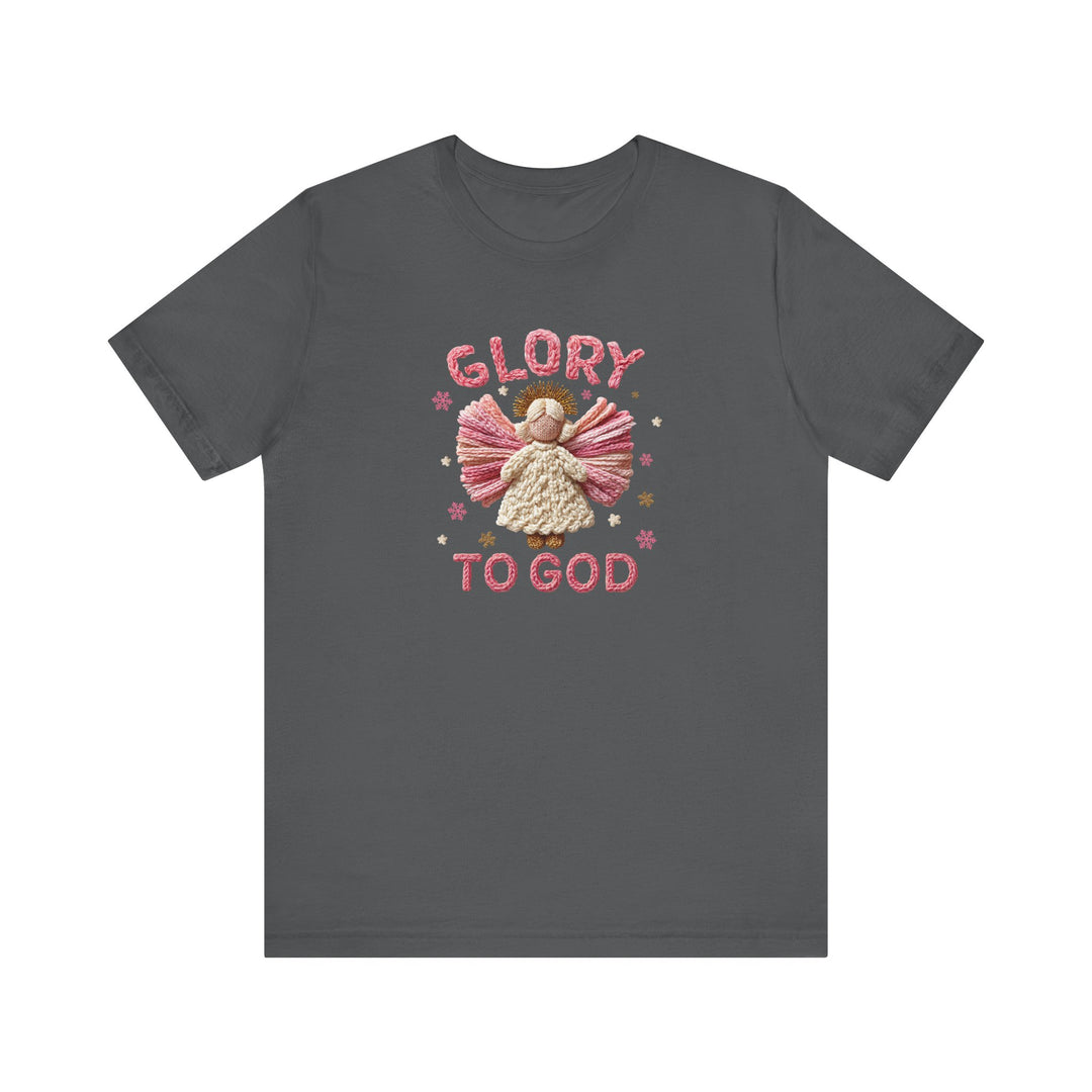 Glory to God Tee: Dark-gray T-shirt with knitted-style angel design, pink wings, cream body, stars, and 'GLORY TO GOD' text, in soft, durable cotton.