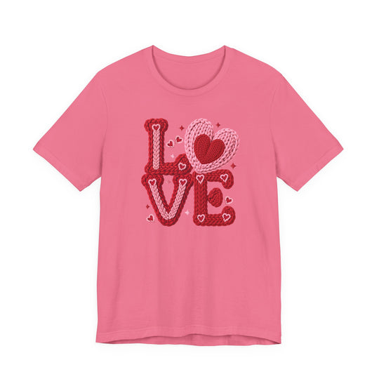 Pink crew-neck tee with LOVE in chunky yarn style, featuring interlocking heart O and floating hearts. Classic fit, soft cotton, from Faith Family Designs.