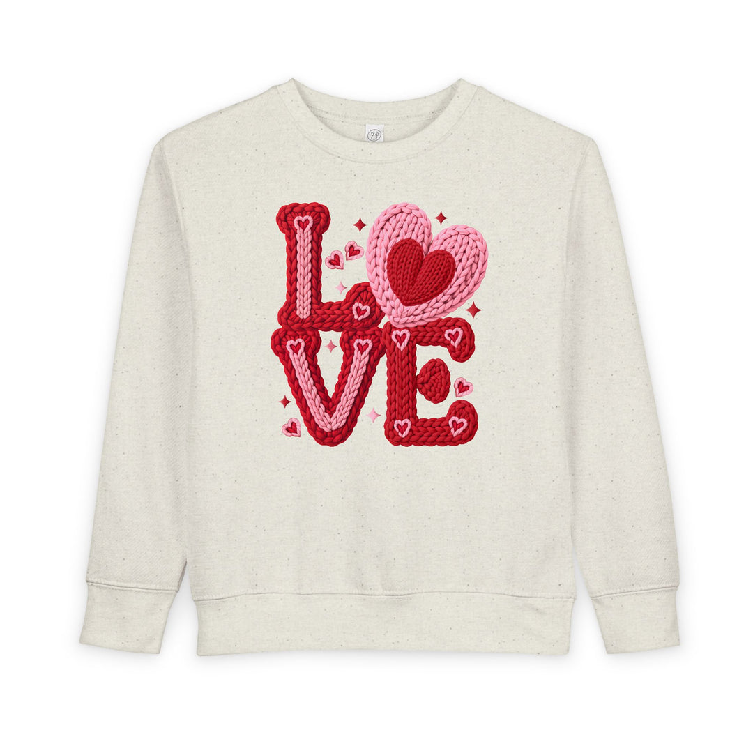 Love Heart Toddler Crew: Off-white sweatshirt with LOVE in red and pink, featuring knitted heart accents. Made from cozy cotton-polyester blend, perfect for toddlers.