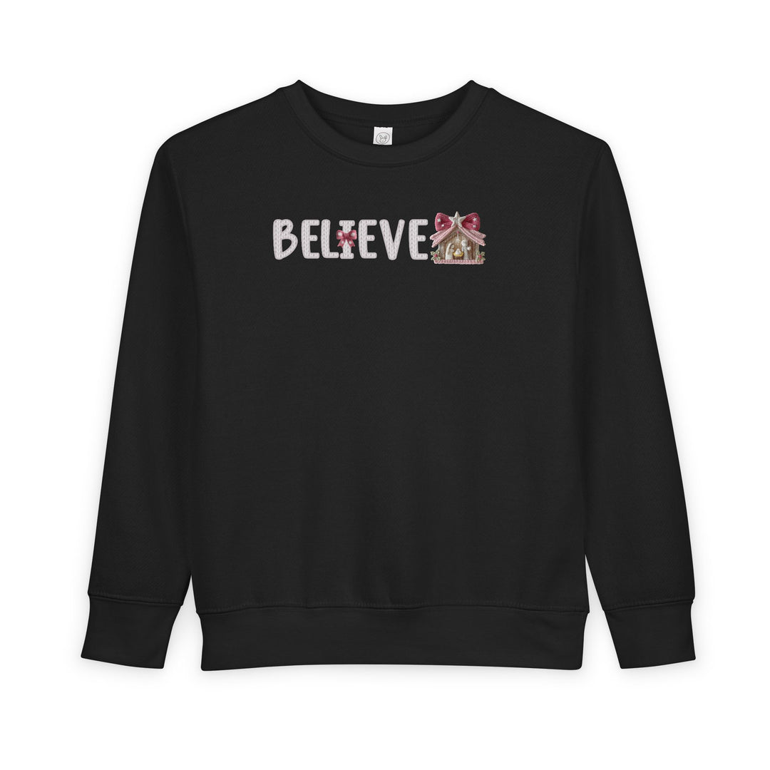 Black Believe toddler crewneck sweatshirt with a candle I and ornament E, designed for comfort and durability, ideal for festive wear from Faith Family Designs.