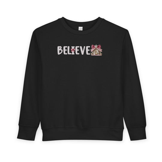 Black Believe toddler crewneck sweatshirt with a candle I and ornament E, designed for comfort and durability, ideal for festive wear from Faith Family Designs.