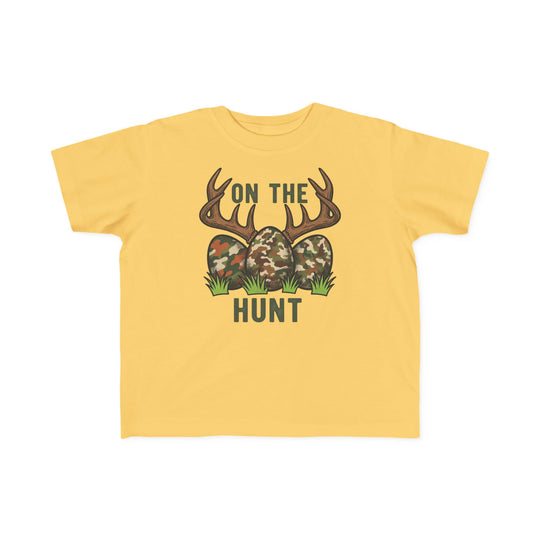 On the Hunt Toddler Tee: Yellow child's T-shirt featuring camouflage eggs with deer antlers and ON THE HUNT text. Soft, durable cotton perfect for toddlers.