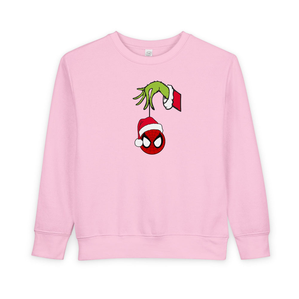 Light-pink toddler sweatshirt features a Grinch-like hand holding a Spider-Man mask ornament. Made from cozy cotton-polyester blend for warmth and comfort.