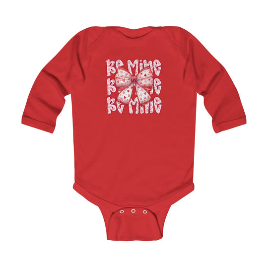 Be Mine Onesie: Red long-sleeved baby bodysuit featuring a pink heart-patterned bow and BE MINE text, with durable snap closures for easy changing.
