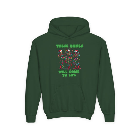 Forest-green youth hoodie featuring dancing skeletons in Santa hats tangled in Christmas lights, with text “THESE BONES WILL COME TO LIFE” above and below the graphic.