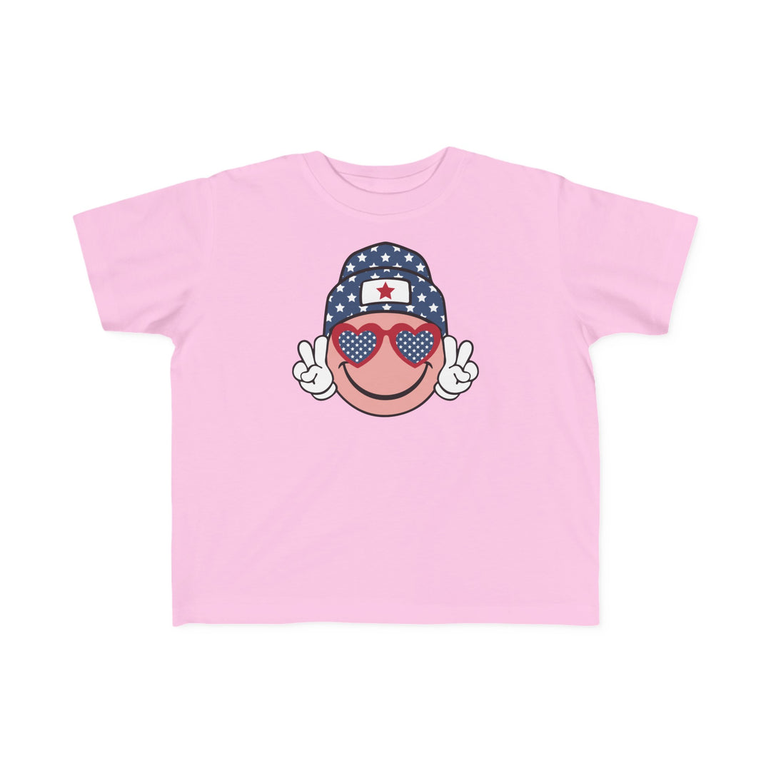 American Girl Toddler Tee featuring a pink shirt with a cartoon face and sunglasses. Soft 100% combed ringspun cotton, light fabric, tear-away label, and classic fit. Sizes: 2T, 3T, 4T, 5-6T.