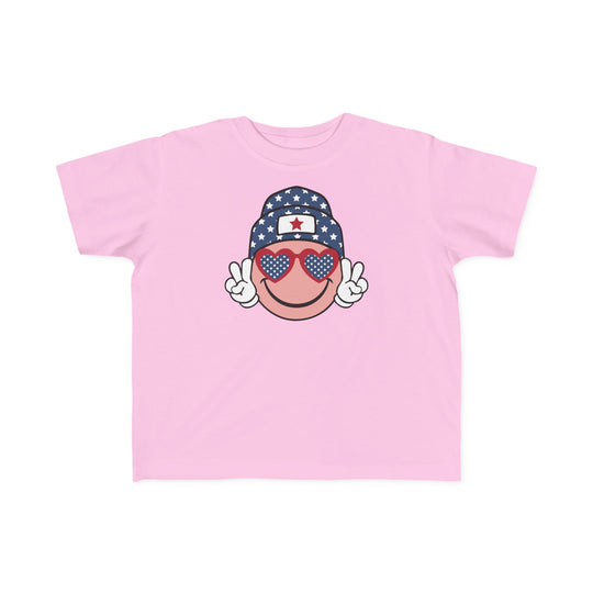 American Girl Toddler Tee featuring a pink shirt with a cartoon face and sunglasses. Soft 100% combed ringspun cotton, light fabric, tear-away label, and classic fit. Sizes: 2T, 3T, 4T, 5-6T.