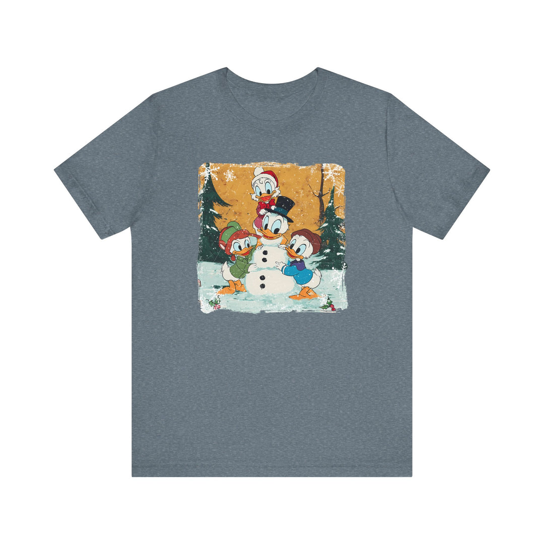 Duck Snowmen Tee featuring Donald Duck and nephews building a snowman in a snowy forest, printed on a slate-blue heather T-shirt.