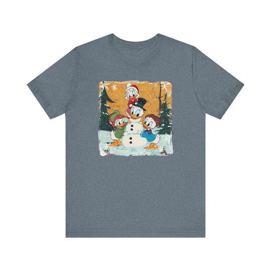Duck Snowmen Tee featuring Donald Duck and nephews building a snowman in a snowy forest, printed on a slate-blue heather T-shirt.