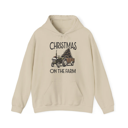 Christmas at the Farm Hoodie featuring a vintage tractor with a Santa hat, pulling a cart with a decorated tree, festive and cozy for winter days.