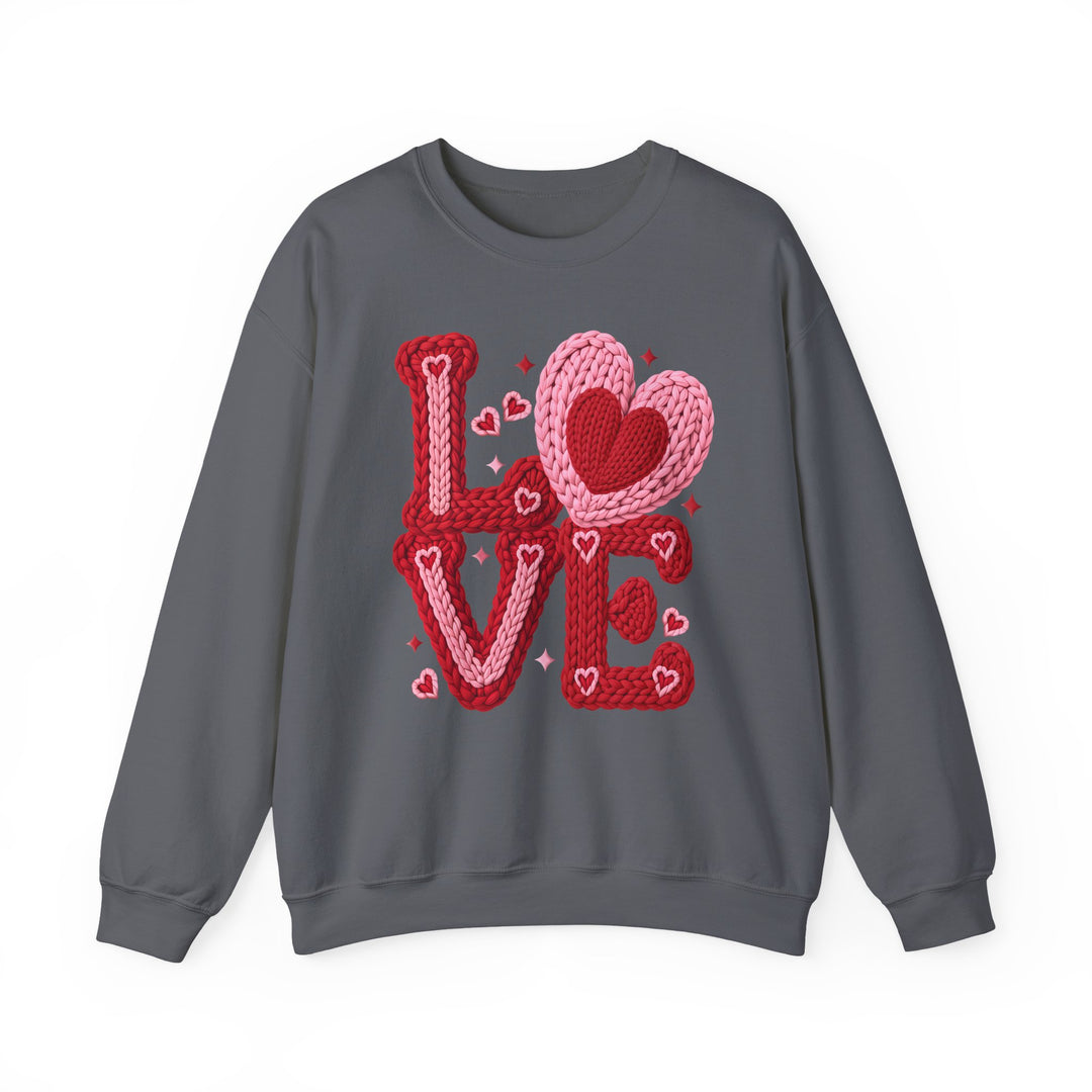 Dark-grey crewneck sweatshirt with LOVE in bulky red and pink knit-style letters, featuring heart accents. Comfortable, unisex fit, ideal for casual wear.