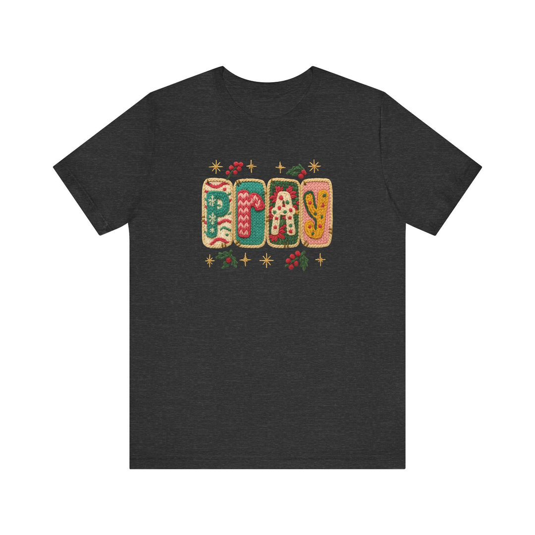Pray Tee features festive cookie-letter design spelling P-R-A-Y with holly accents on a dark-charcoal crew-neck. Soft, unisex fit, perfect for holiday wear.