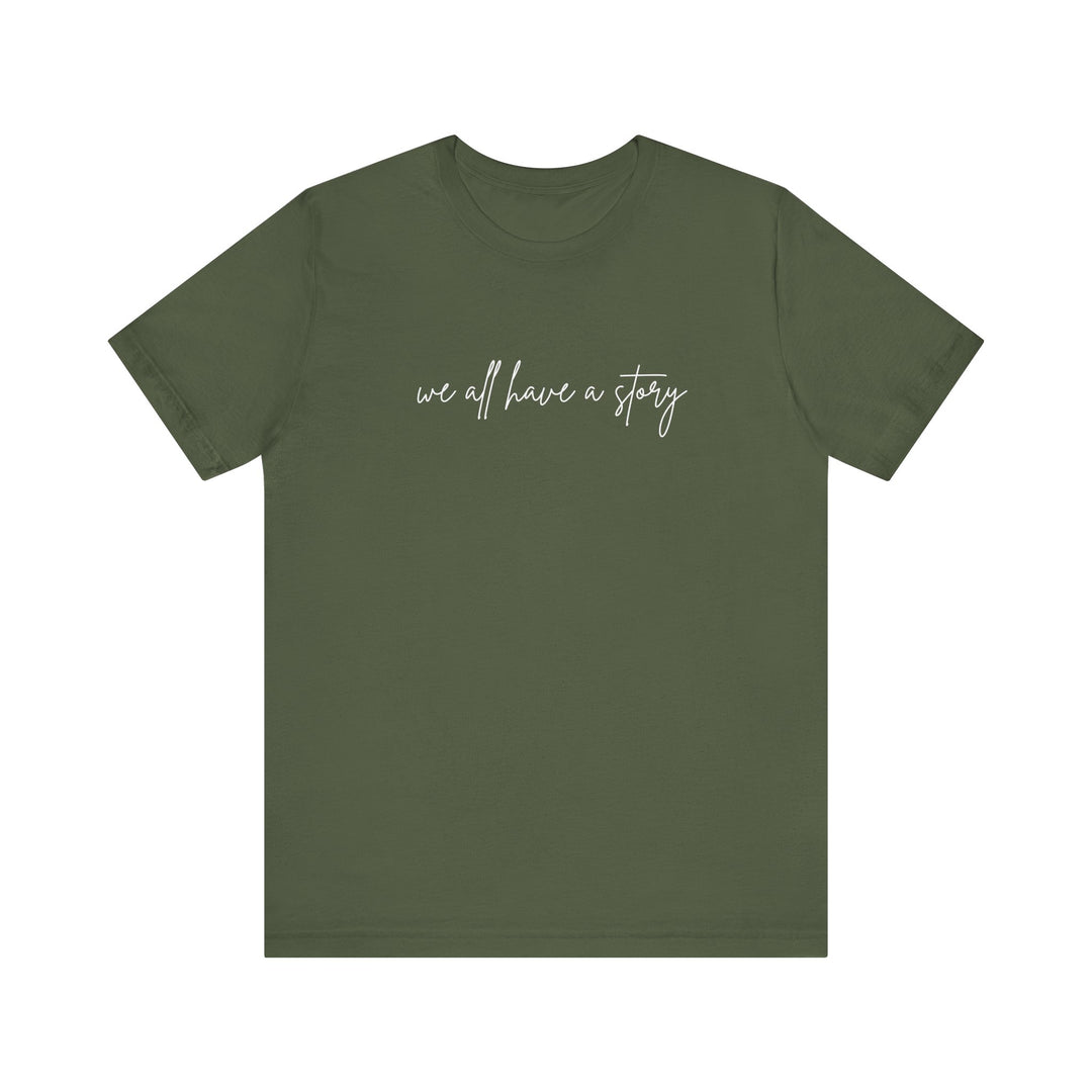We all have a Story Tee, green with white text, featuring a classic unisex fit and soft cotton fabric, perfect for casual wear.