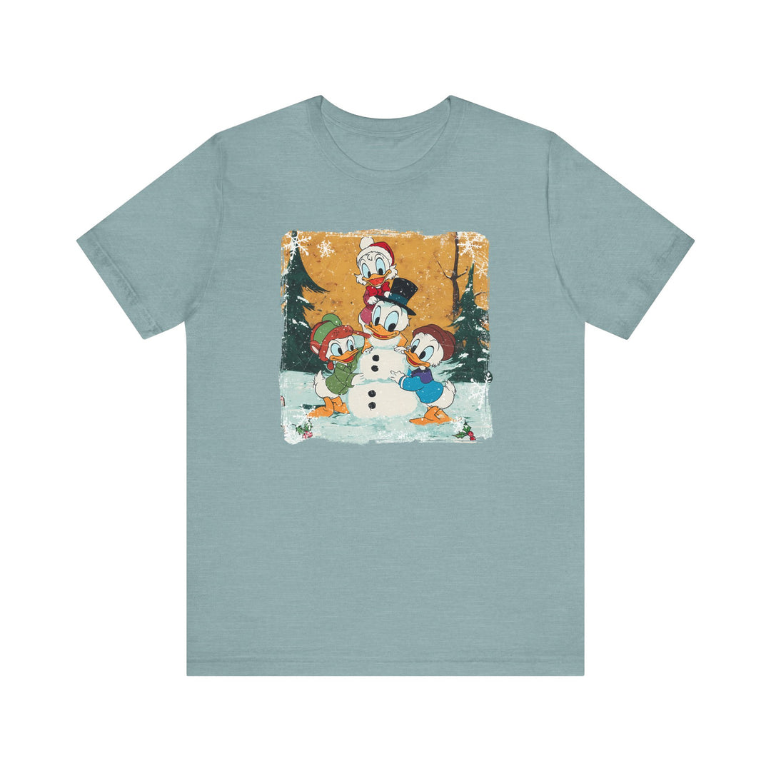 Duck Snowmen Tee featuring Donald Duck and friends building a snowman in a snowy forest. Vintage, distressed design on a soft, unisex cotton shirt.