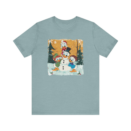 Duck Snowmen Tee featuring Donald Duck and friends building a snowman in a snowy forest. Vintage, distressed design on a soft, unisex cotton shirt.