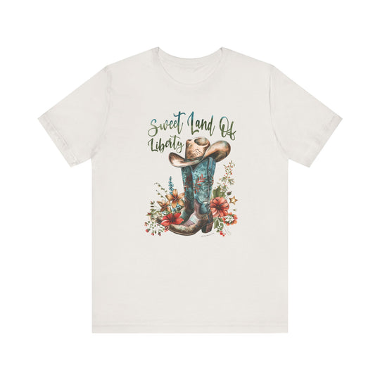 A white t-shirt featuring a cowboy hat and flowers, embodying a classic Americana vibe. Unisex jersey tee with ribbed knit collars, taping on shoulders, and tear-away label. 100% Airlume combed cotton, light fabric, retail fit.
