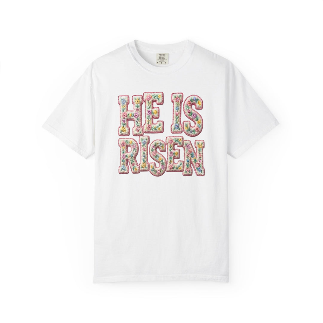 White crew-neck T-shirt with HE IS RISEN in pastel floral pattern, reflecting the Faith Family Designs' unique graphic style and spiritual theme.