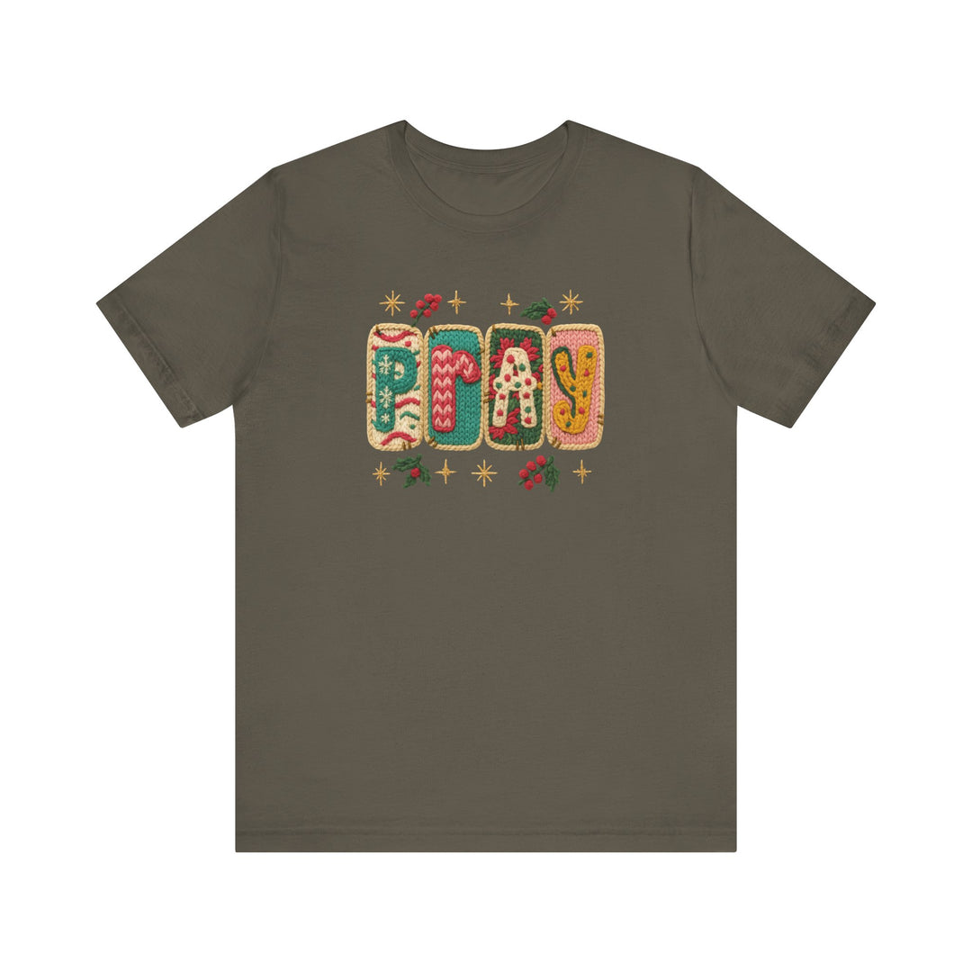 Pray Tee: Olive-green crew-neck displaying PRAY in festive knit-style graphics with holiday motifs. Cozy, unisex fit, crafted from soft cotton.