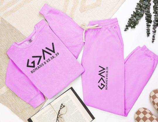 God is Greater Sweatpants, showcasing black text on pink fabric. Made from ringspun cotton, these relaxed-fit, garment-dyed sweatpants offer a vintage, retro-inspired look.