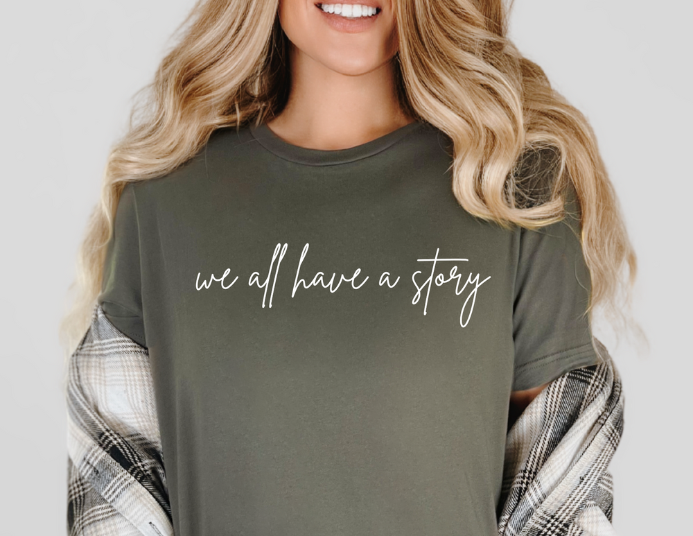 A woman in a casual setting wearing the We all have a Story Tee, showcasing its comfortable fit and soft fabric, perfect for everyday wear.