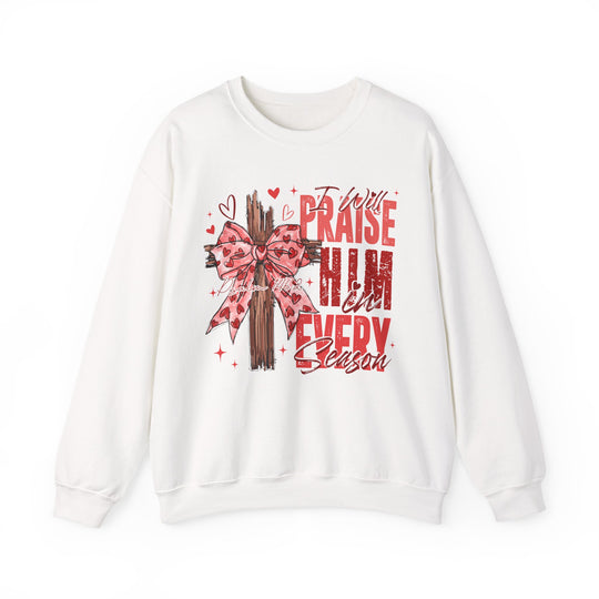 Praise in Every Season Heart Crew sweatshirt features a wooden cross with a pink bow and red text, combining comfort with a spiritual message.