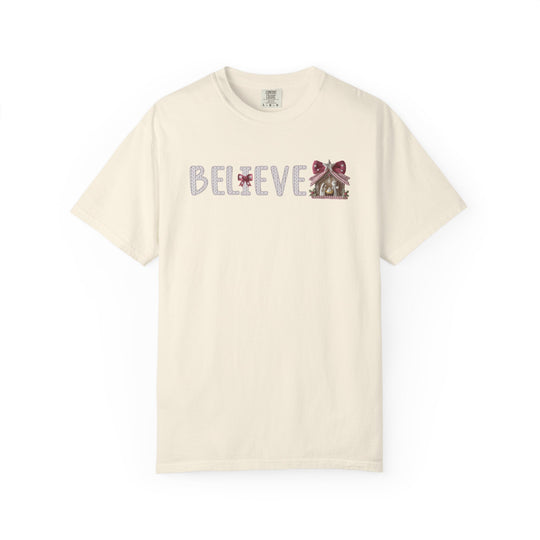 Unisex Believe T-shirt with knitted-look letters and nativity scene, featuring red bows. Classic crew-neck design, perfect for holiday festivities.