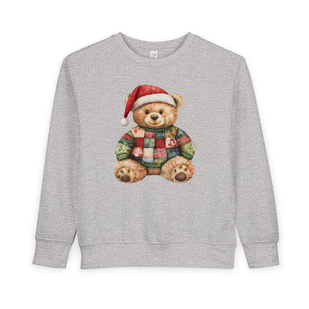 Christmas Bear Toddler Crew sweatshirt featuring a teddy bear in a Santa hat and patchwork sweater, on a light gray background. Cozy, durable, and stylish for toddlers.