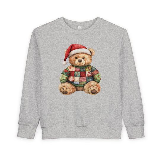 Christmas Bear Toddler Crew sweatshirt featuring a teddy bear in a Santa hat and patchwork sweater, on a light gray background. Cozy, durable, and stylish for toddlers.