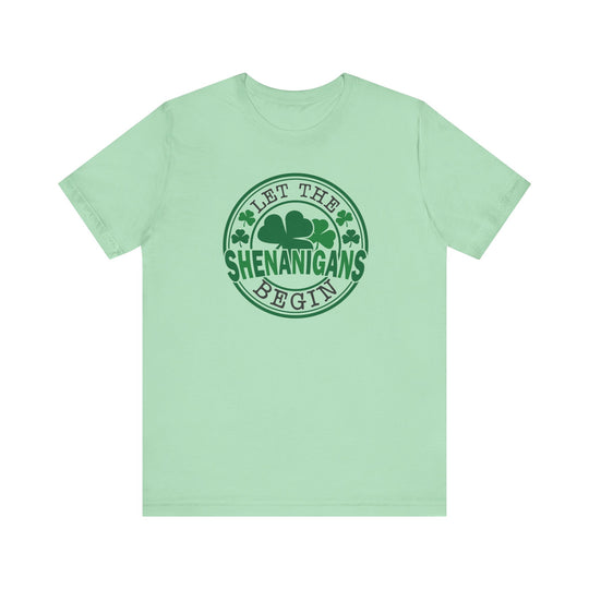 Let The Shenanigans Begin Tee features a green logo with four-leaf clovers, perfect for casual wear with ribbed knit collars and durable side seams.