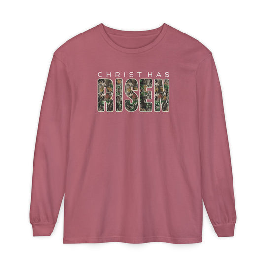 Christ has Risen Long Sleeve Tee: Dusty rose long-sleeve T-shirt with CHRIST HAS RISEN text, featuring woodland camouflage pattern, 100% cotton, relaxed fit.