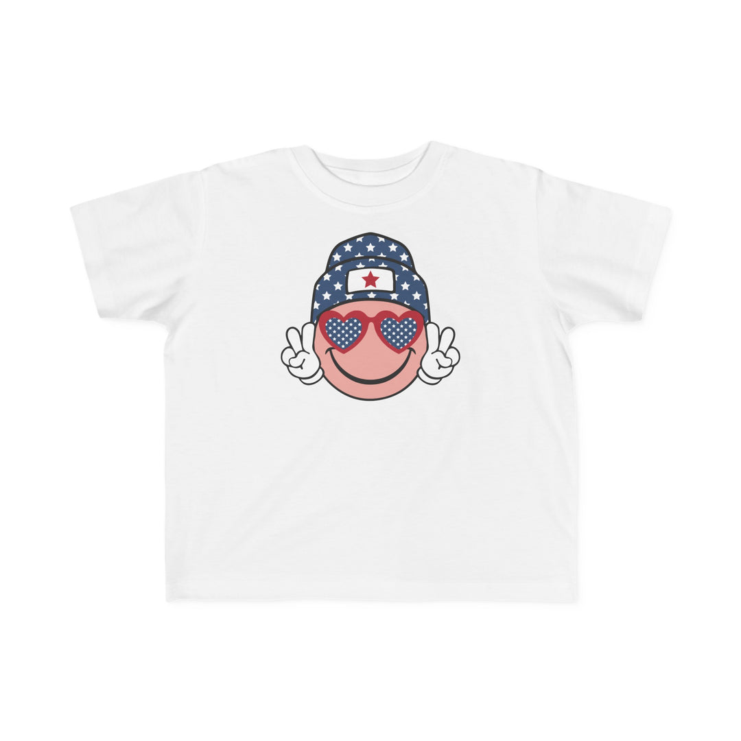 American Girl Toddler Tee featuring a cartoon face with sunglasses and a hat on a white shirt. Soft 100% combed ringspun cotton, tear-away label, classic fit. Available in sizes 2T to 5-6T.