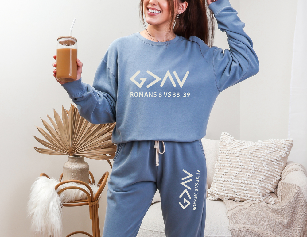 Woman holding a glass of brown liquid, showcasing the God is Greater Sweatpants, made from American-sourced ring-spun cotton with a vintage garment-dyed finish.