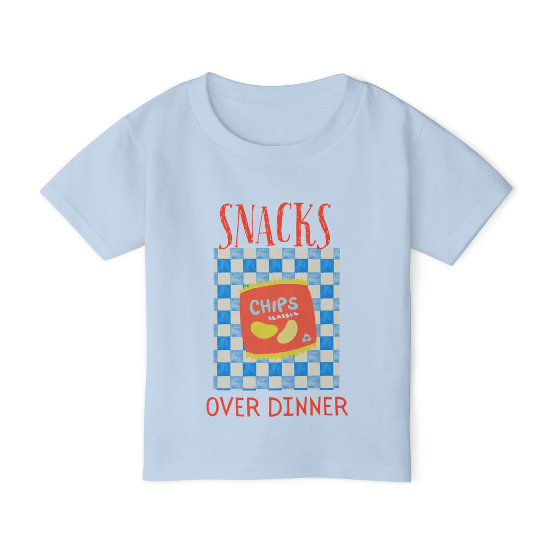 Heavy Cotton™ Toddler T-shirt featuring a playful snack-themed design with SNACKS OVER DINNER and a red bag of chips on a checkerboard background.