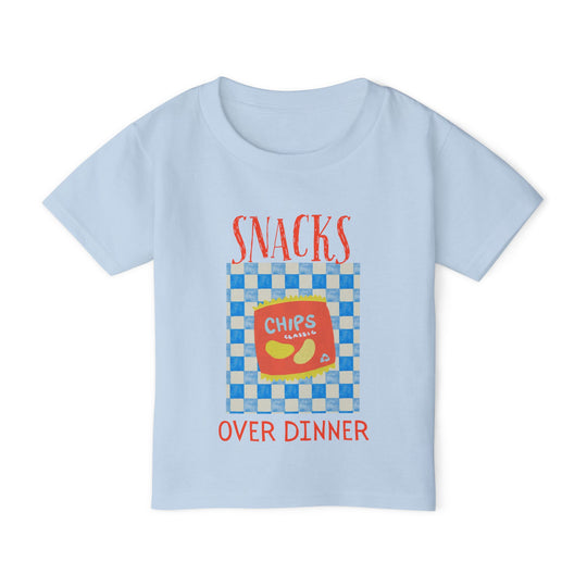 Heavy Cotton™ Toddler T-shirt featuring a playful snack-themed design with SNACKS OVER DINNER and a red bag of chips on a checkerboard background.