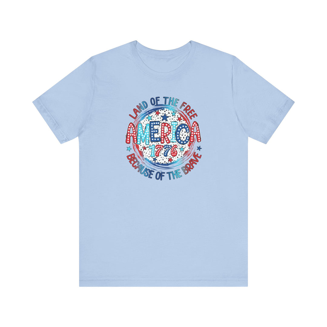 A unisex America 1776 Tee, featuring red, white, and blue text on a blue shirt. 100% Airlume combed cotton, retail fit, tear away label, and ribbed knit collars for comfort. Sizes XS to 3XL.