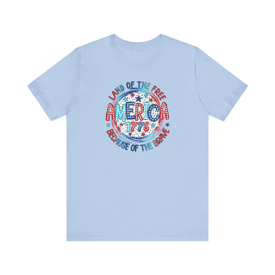 A unisex America 1776 Tee, featuring red, white, and blue text on a blue shirt. 100% Airlume combed cotton, retail fit, tear away label, and ribbed knit collars for comfort. Sizes XS to 3XL.