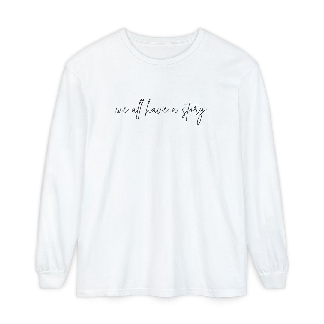 We all have a Story Long Sleeve Tee: A white, long-sleeved shirt featuring black text, crafted from 100% ring-spun cotton for a relaxed fit and comfort.