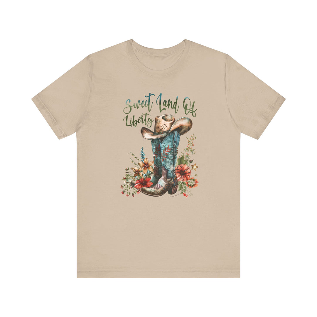 A tan t-shirt featuring a cowboy hat and flowers, embodying a classic Americana vibe. Unisex jersey tee made of 100% cotton, with ribbed knit collars and taping on shoulders for lasting comfort and fit.