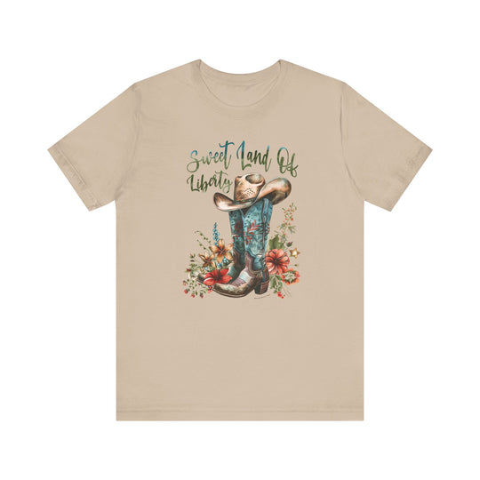 A tan t-shirt featuring a cowboy hat and flowers, embodying a classic Americana vibe. Unisex jersey tee made of 100% cotton, with ribbed knit collars and taping on shoulders for lasting comfort and fit.