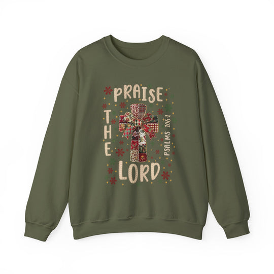 Olive-green crewneck sweatshirt with a patchwork cross, snowflake motifs, “PRAISE THE LORD” text, and Psalms 106:1 reference, from Faith Family Designs.