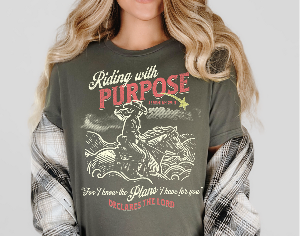 Riding for a Purpose Tee: A woman wears a green t-shirt featuring a graphic of a person riding a horse, showcasing a classic, casual style.