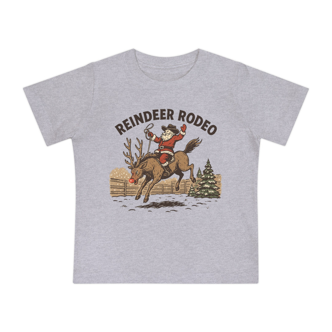 Reindeer Rodeo Baby Tee: Light gray T-shirt featuring Santa in cowboy attire atop a reindeer, blending Christmas and Western themes. Ideal for stylish, comfortable baby wear.