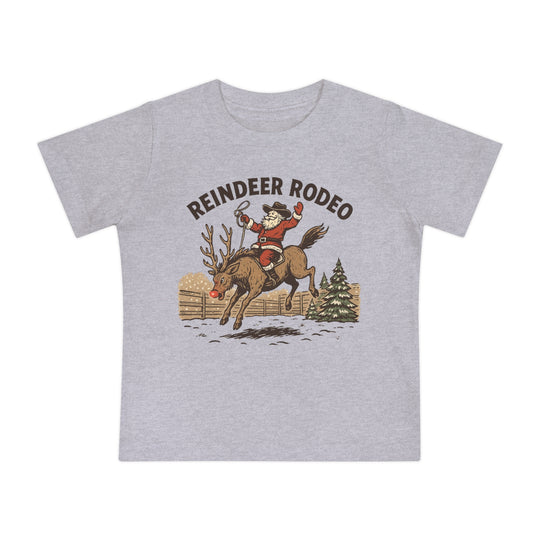 Reindeer Rodeo Baby Tee: Light gray T-shirt featuring Santa in cowboy attire atop a reindeer, blending Christmas and Western themes. Ideal for stylish, comfortable baby wear.