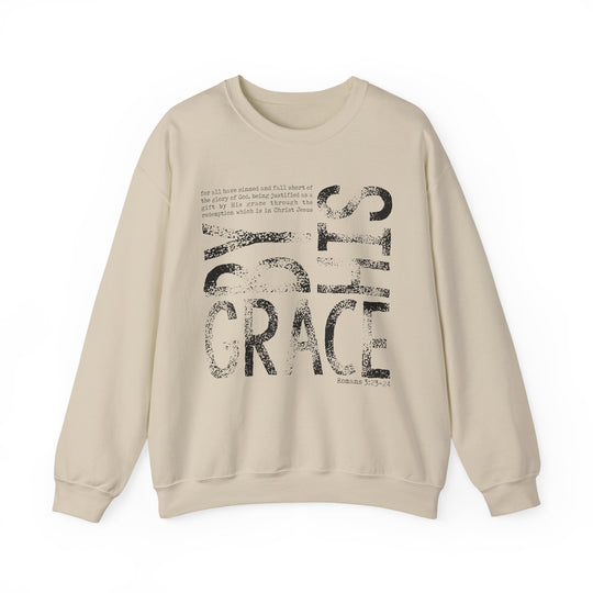 Cream-colored sweatshirt with BY GRACE in bold letters and Romans 3:23–24 verse, offering comfort and style with a durable, ethically made fabric blend.