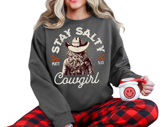 Woman in a Stay Salty Crew sweatshirt with a cowboy hat, sitting on a chair, holding a mug. The sweatshirt offers a comfortable fit and unique design.