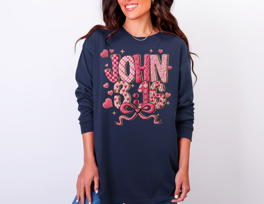 Person wearing a navy 3:16 Long Sleeve Tee with pink-and-red patterned JOHN 3:16 graphic, featuring hearts and sparkles, on a light background.
