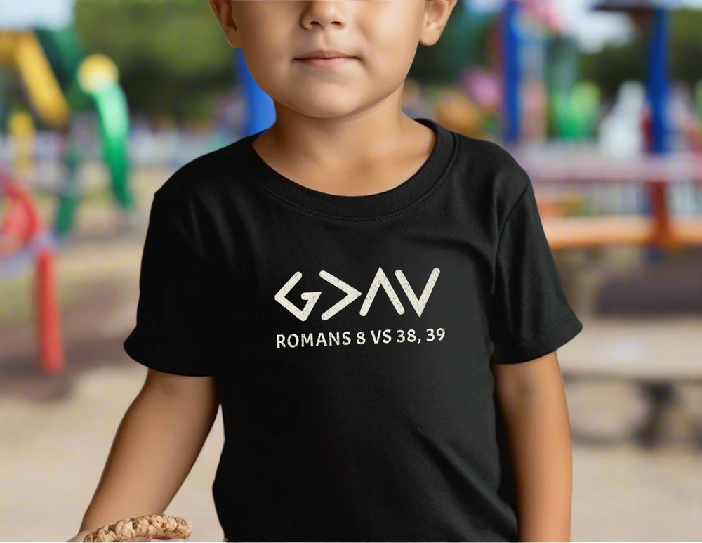 Toddler wearing the God is Greater Tee, standing near pumpkins, showcasing the shirt's soft cotton fabric and classic fit ideal for sensitive skin.