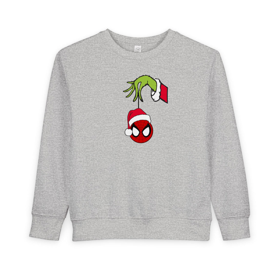 Spider Ball Christmas Toddler Crew: Light-gray sweatshirt featuring the Grinch's hand holding a Spider-Man ornament, perfect for festive, cozy wear.