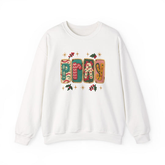 White crewneck sweatshirt with PRAY in colorful knit-style blocks, adorned with holly sprigs and starburst motifs, offering a festive, holiday-themed look.
